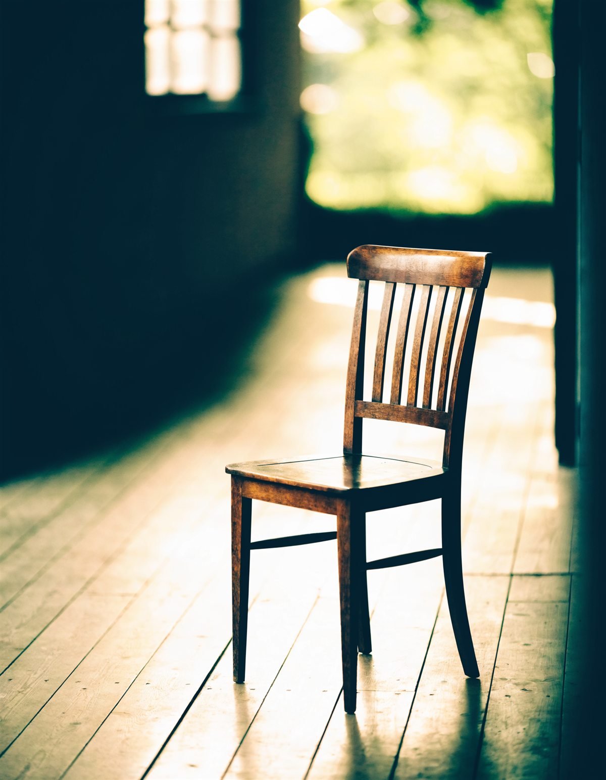 An empty wooden chair in warm window light
