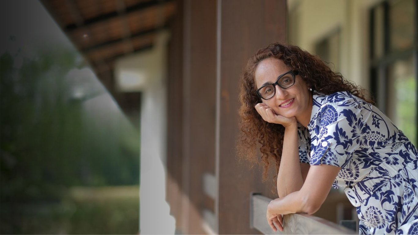 Dr. Sabiha leaning on a railing in warm daylight